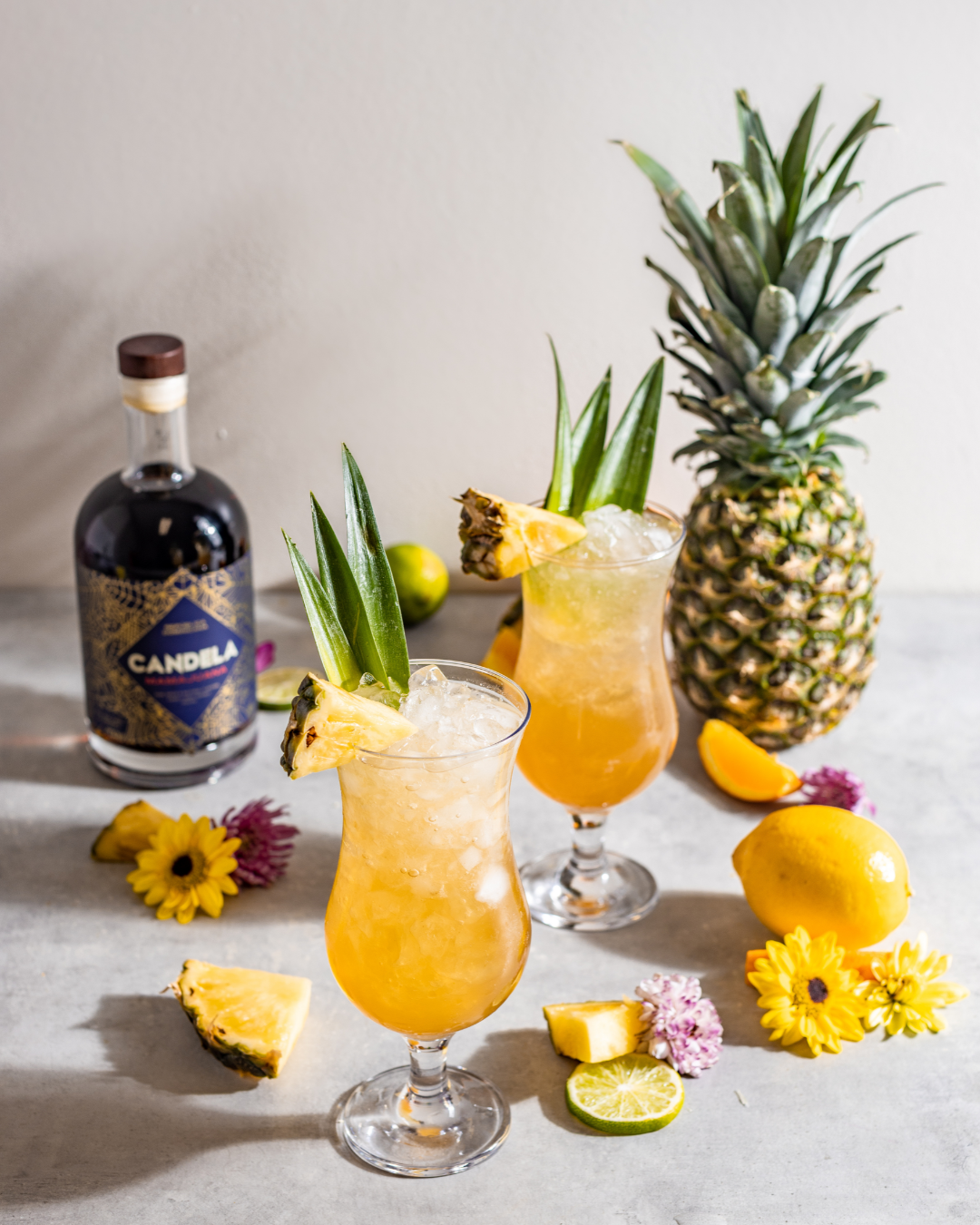 Mamajuana Cocktails by Candela Mamajuana, featuring the "Mama Tai" recipe, a Mai Tai Recipe with Spiced Rum called MamaJuana from the Dominican Republic. Cocktails shown with fresh fruit like pineapple, orange, and lemon, a beautiful summer cocktail